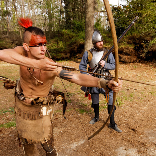 A Powhatan interpreter draws a bow and arrow next to an English colonist interpreter