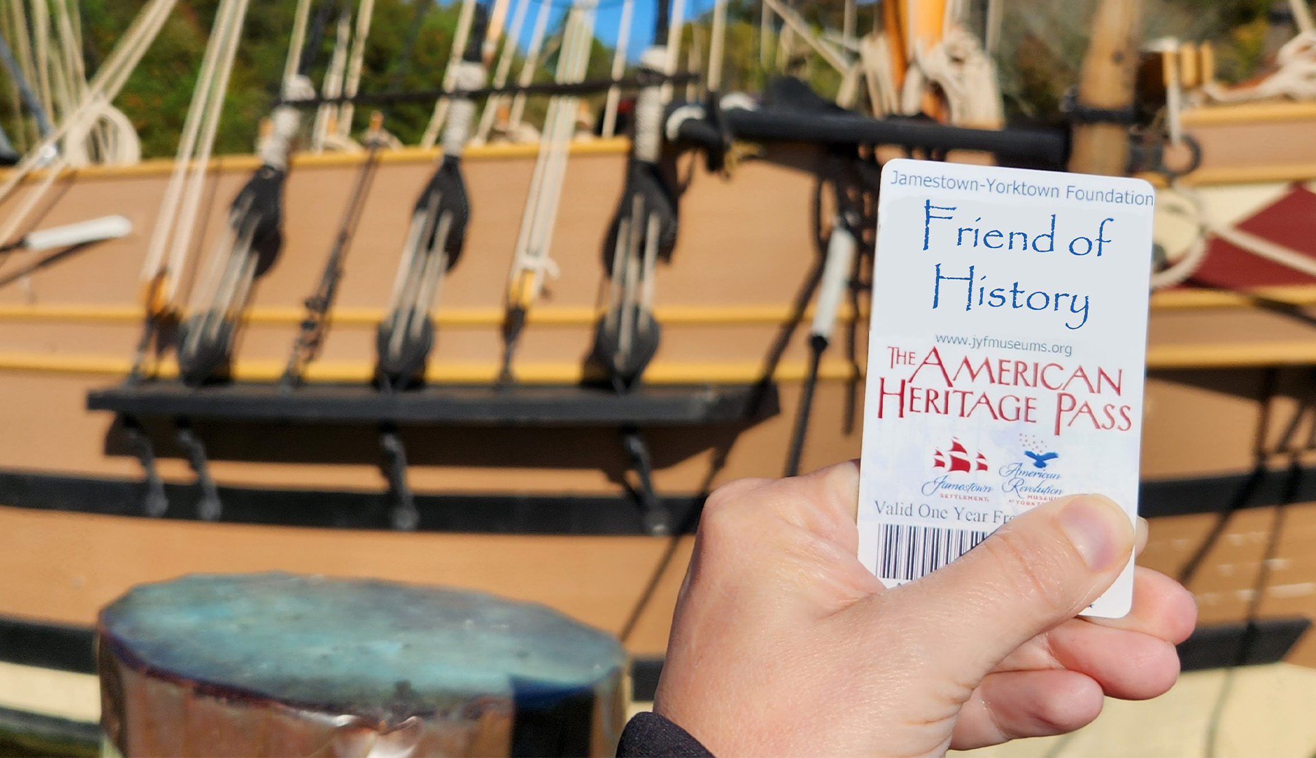 An annual pass card being held in front of a ship