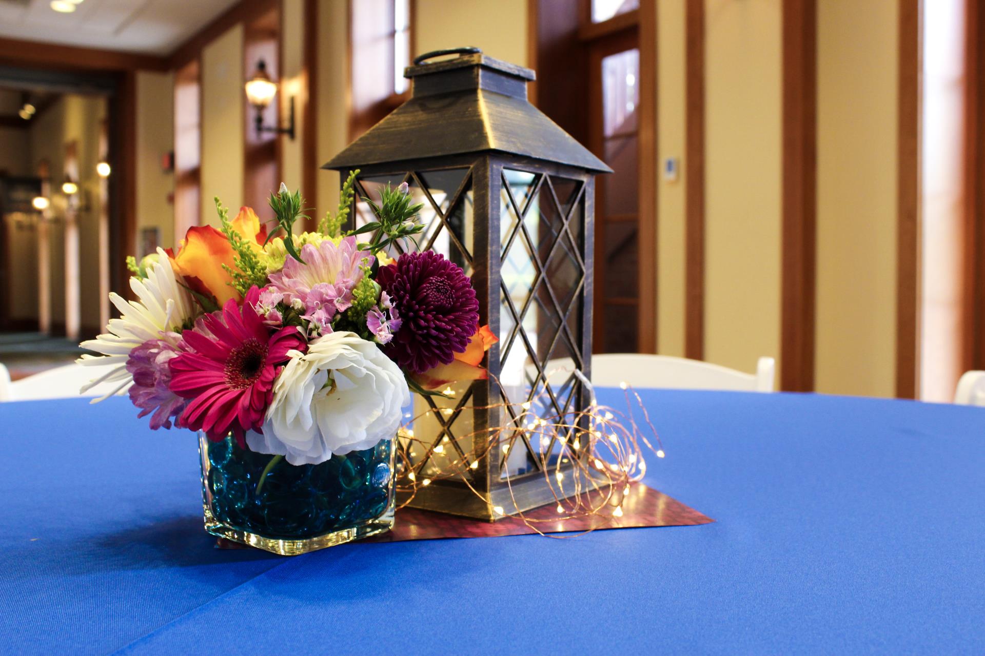 An antique lantern and floral arrangement on a table