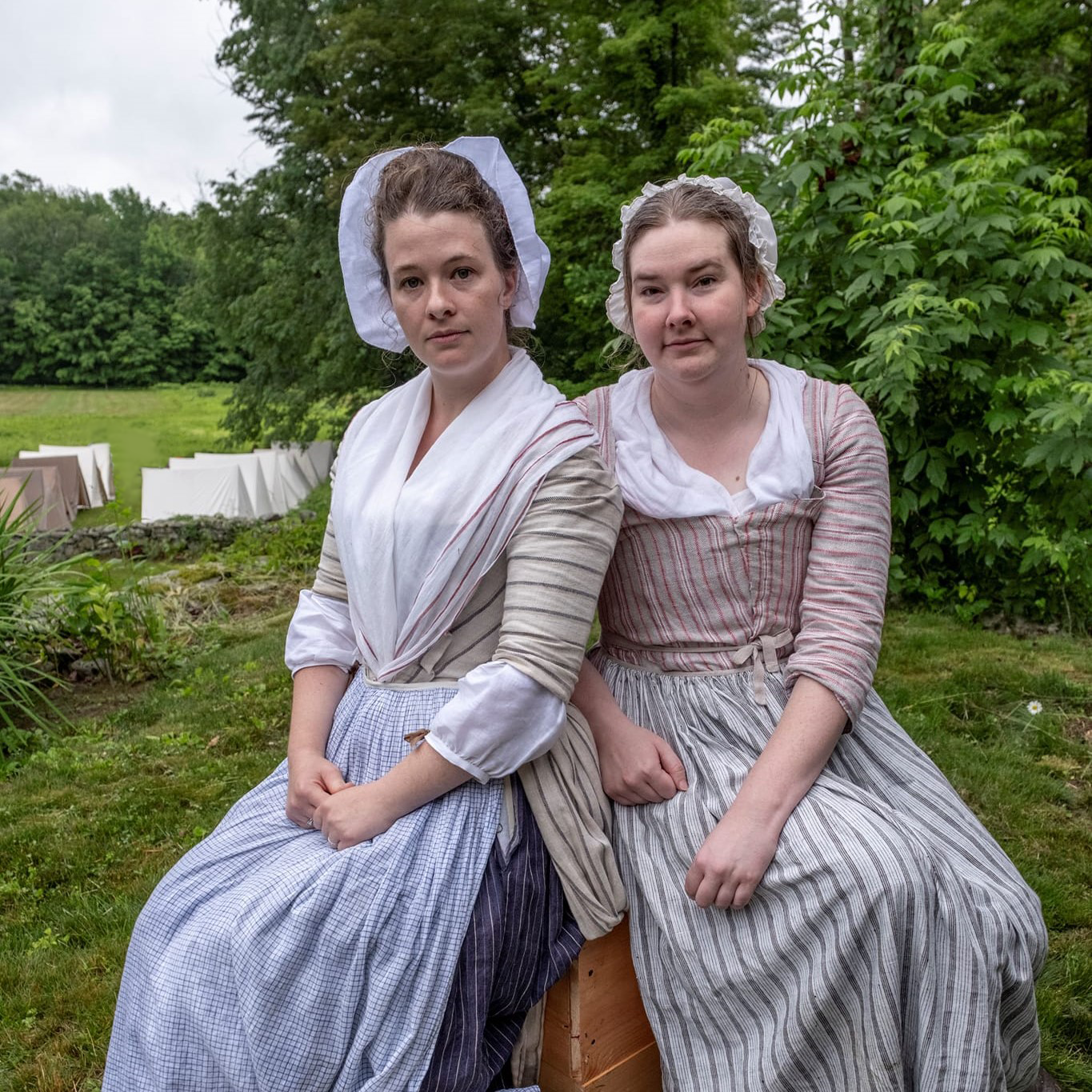 Two women in colonial American clothing seated outdoors