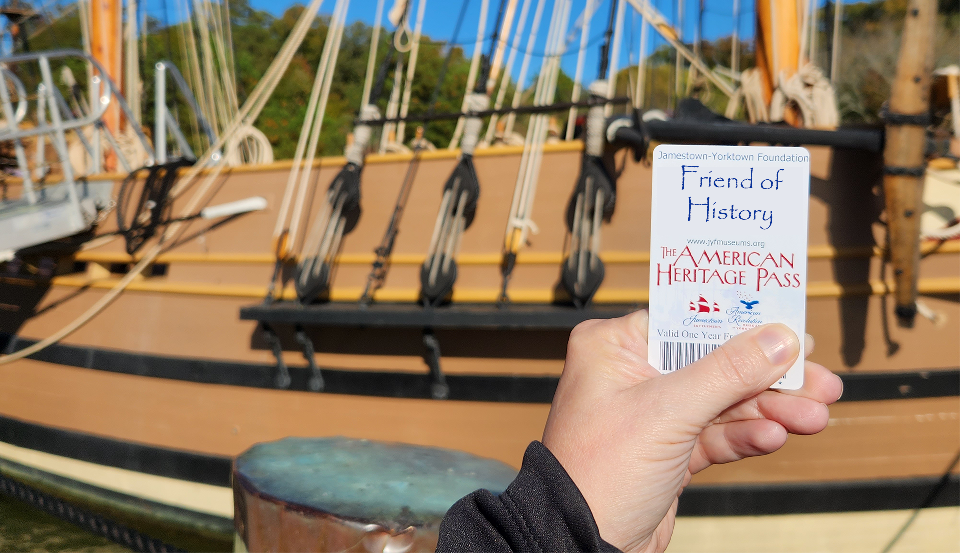 An Annual Pass being held in front of a ship